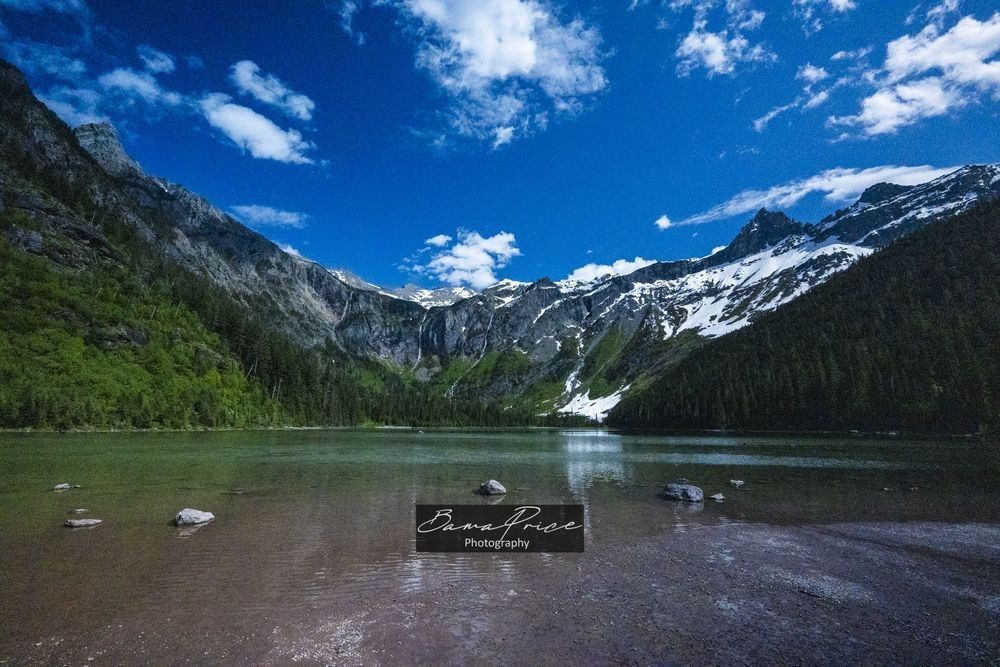 Avalanche Lake surrounded by towering mountains, waterfalls and evergreen forest in Glacier National Park, Montana.