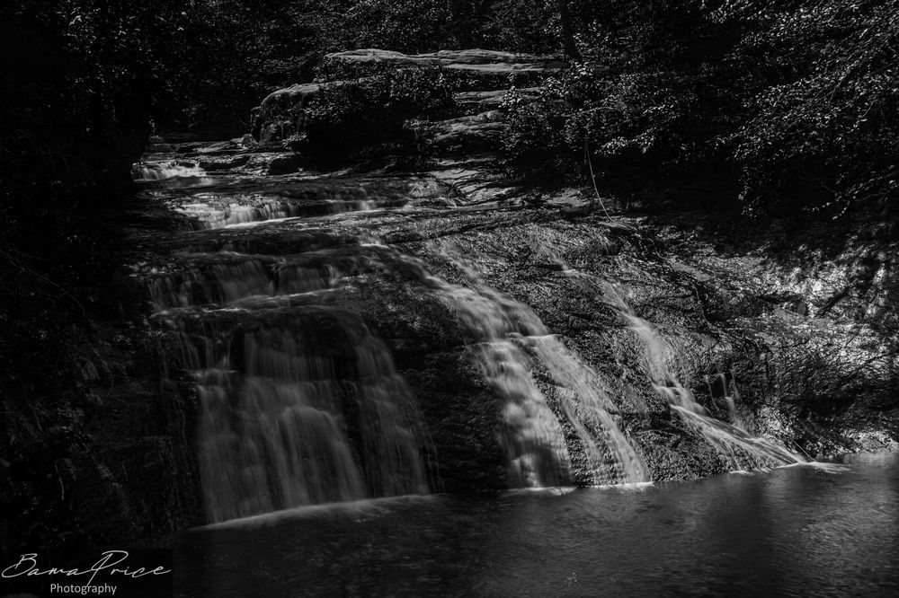 Long-exposure fine art photograph of Kinlock Falls, Alabama — water cascading in silky ribbons over tiered limestone ledges, surrounded by lush summer forest. Silver-toned print by Bama Price Photography.