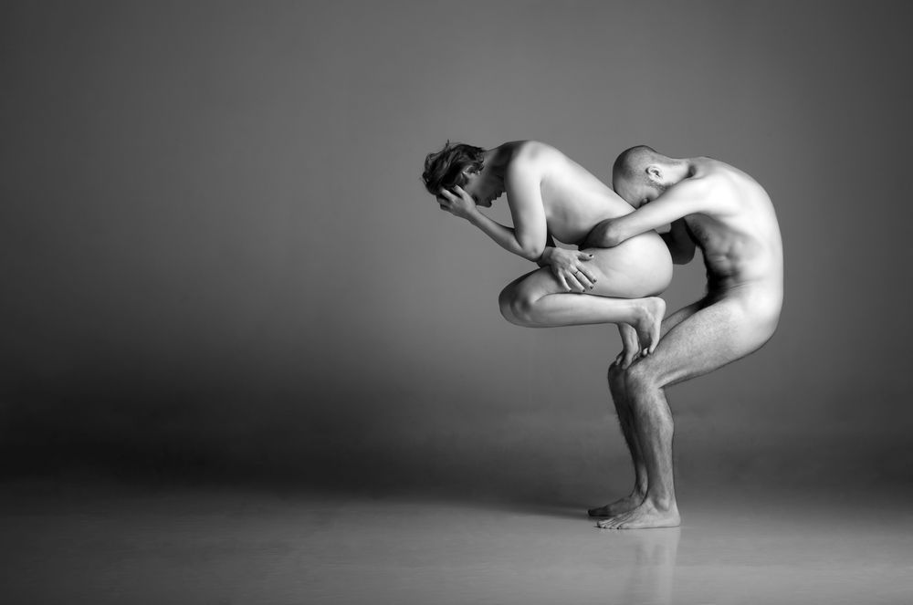 A black and white infrared portrait of a couple holding each other in an acrobatic pose