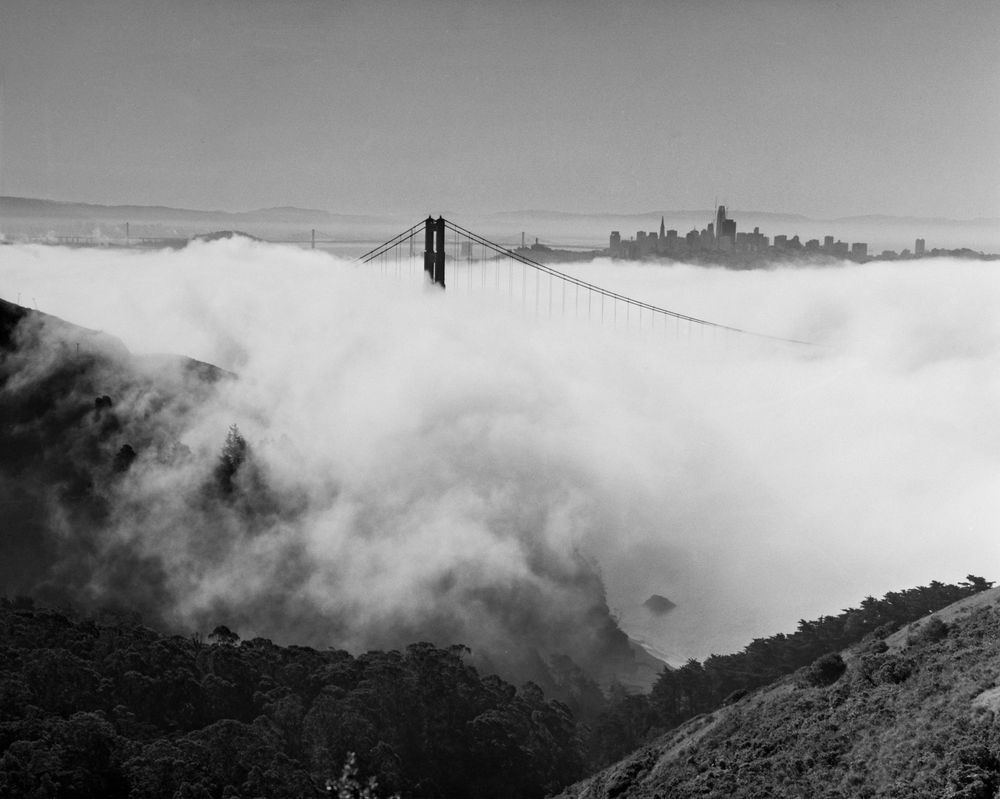 A black and white photograph of the Golden Gate Bridge covered in fog