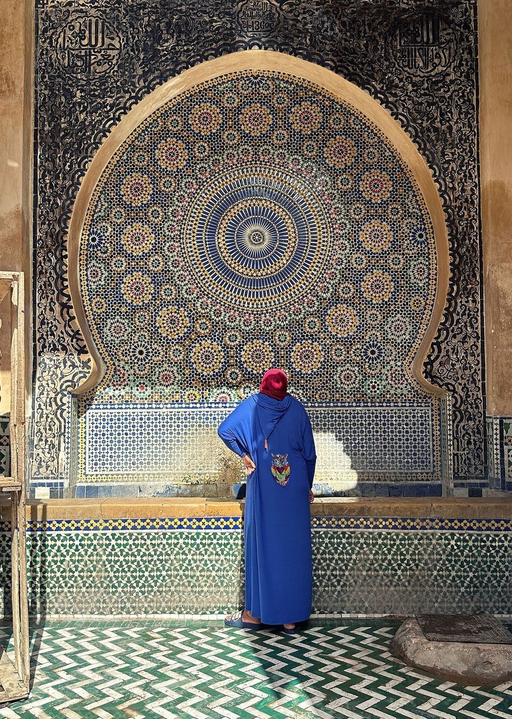 Woman standing in a narrow blue-painted passageway in Fez, Morocco.