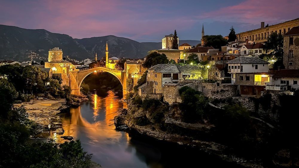 Illuminated Stari Most bridge at dusk over the Neretva River in Mostar, Bosnia and Herzegovina.