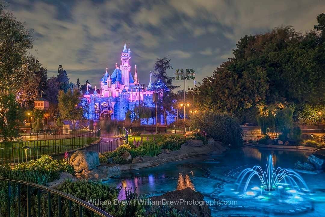 Sleeping Beauty Castle at night glowing pink and blue with fountain reflections – Disneyland fine art photography