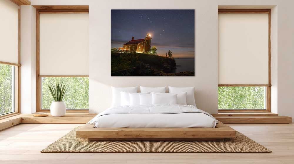 Alt text: Dipper Over Eagle Harbor lighthouse print hanging as wall art above a bed in a modern bedroom