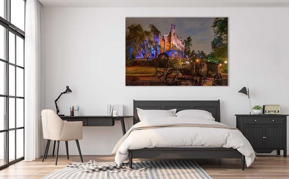 Disney's Haunted Mansion at Night wall art above a bed in a modern bedroom