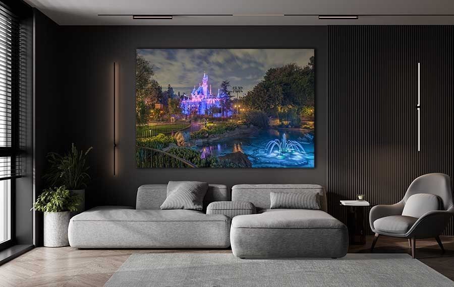 Beautiful Sleeping Beauty Castle canvas print displayed as large wall art above a gray sectional sofa in a modern dark-walled living room