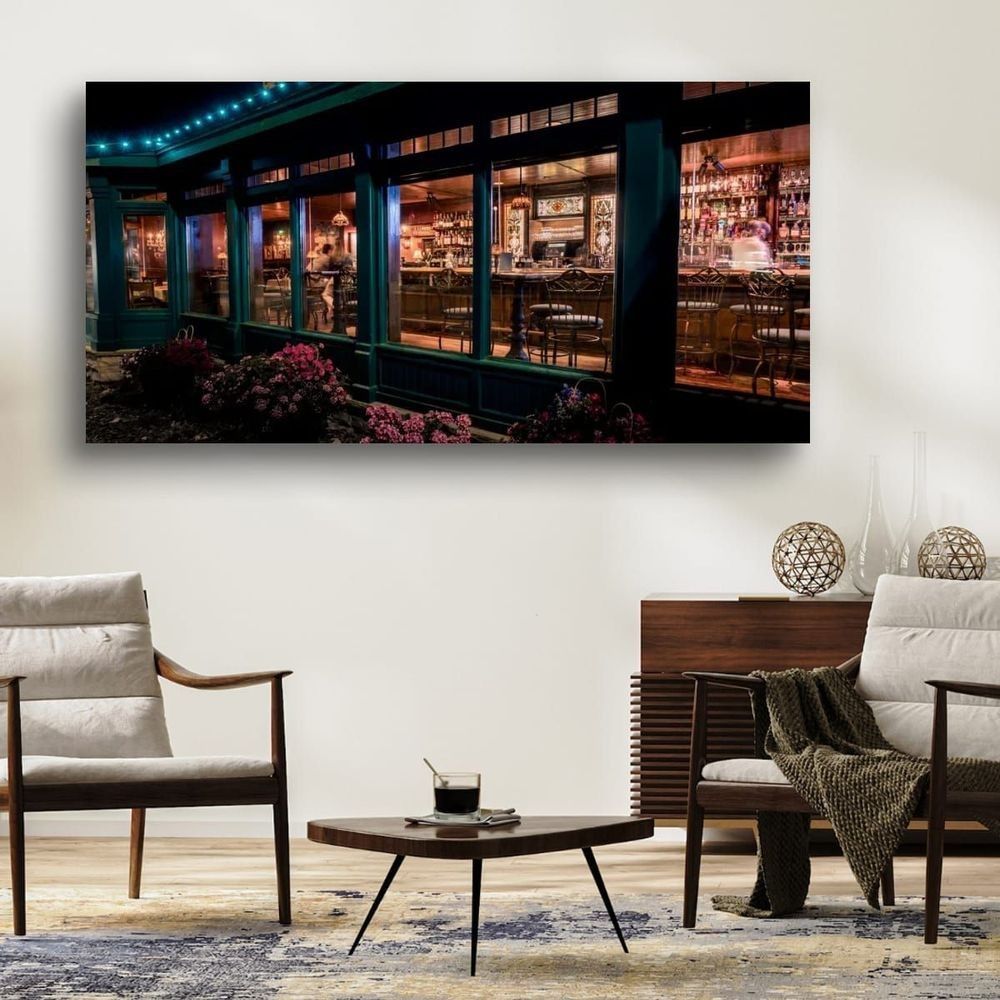 Framed panoramic print of the Nicollet Island Inn at night, "Nicollet Island Nights" by William Drew, displayed above a coffee table in a modern living room