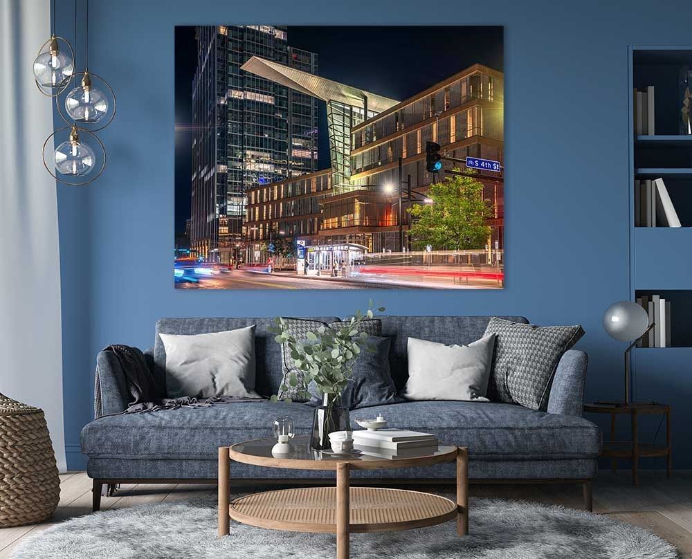 Downtown Convergence print displayed above a sofa in a blue-walled living room, Minneapolis Central Library night photography
