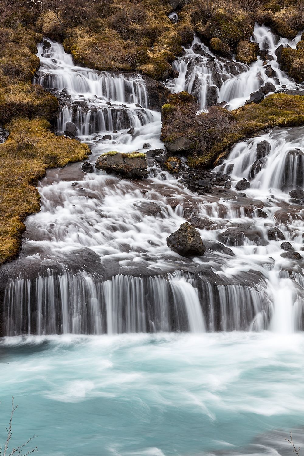 Groundwater emerging through rock layers forming cascading spring-fed flow and surface stream system
