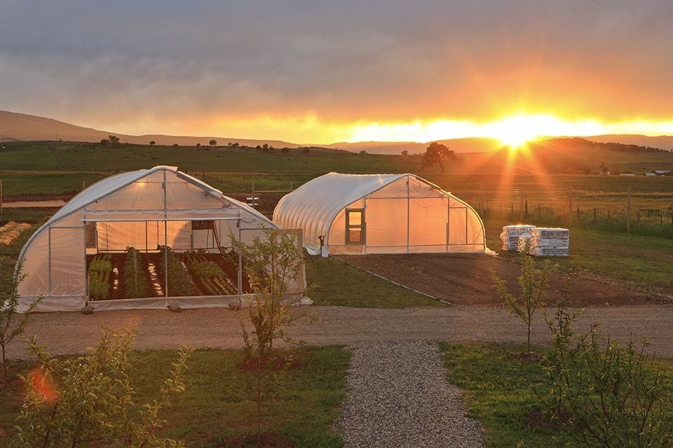 Divide Creek Farm in Colorado at sunset with greenhouses, fields, soil, sunlight, and regenerative farming systems representing Quantum Agriculture
