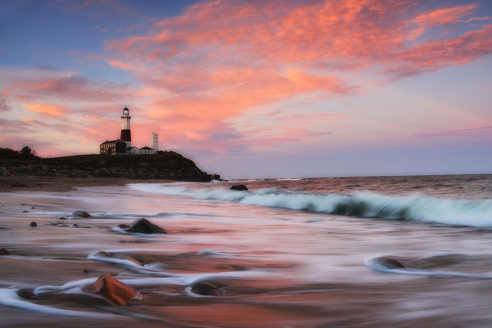 Montauk Lighthouse at sunrise with ocean waves, rocky shoreline, and coastal atmosphere showing ocean-land interaction, tidal energy, and coastal wildlife habitat