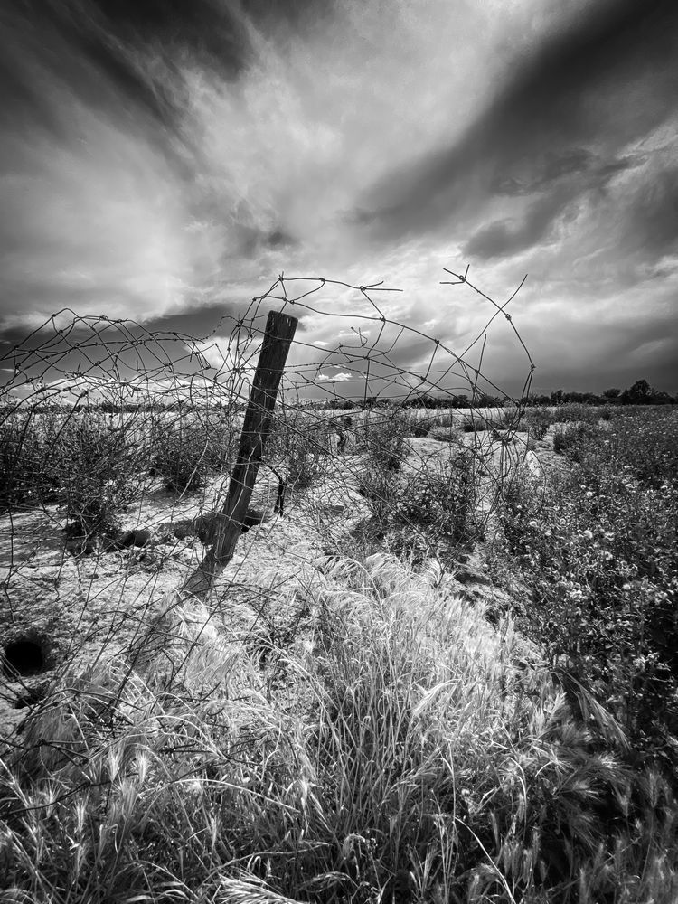 A barbed-wire post juts into the sky as a storm front passes through Yolo County, California.