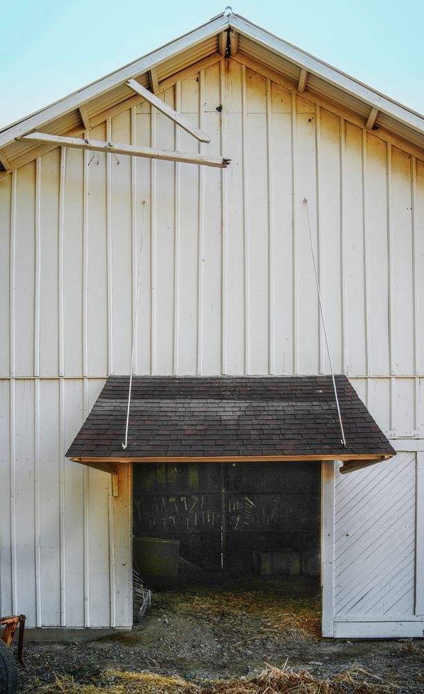 Dim outlines of farm tools where they once hung can be seen through a barn door at Pollock Farm.