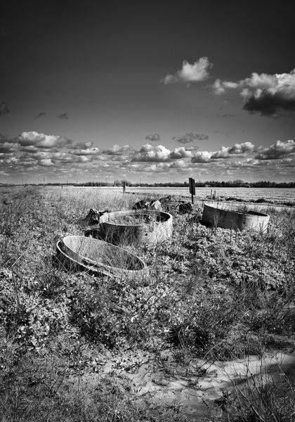 Three sections of concrete culverts lie unused along row-crop fields in Yolo County, California.