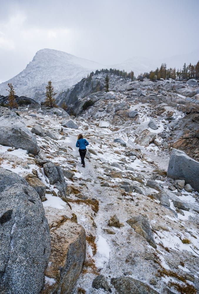 Woman walking up a trail in a snow squall, Enchantment Lakes Wilderness Area, Washington Cascades, USA.