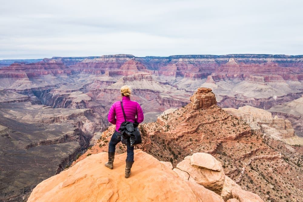 A woman standing at the edge of a precipice Grand Canyon National Park, Arizona, USA.