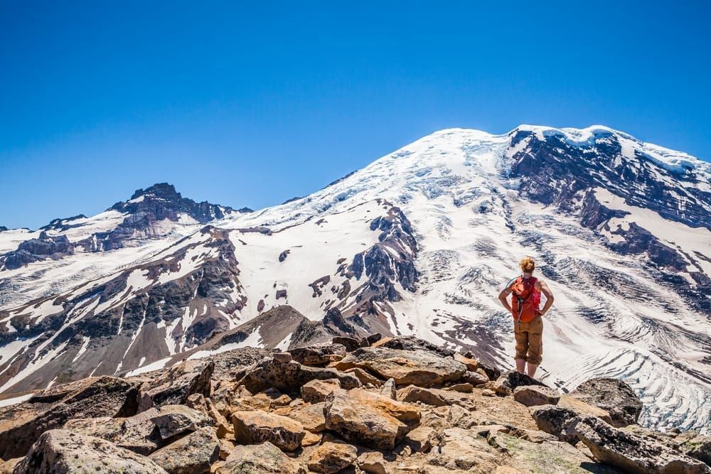 A woman hiker scrambling over the rocks on 3rd Burroughs Mountain, Mount Rainier National Park, Washington, USA