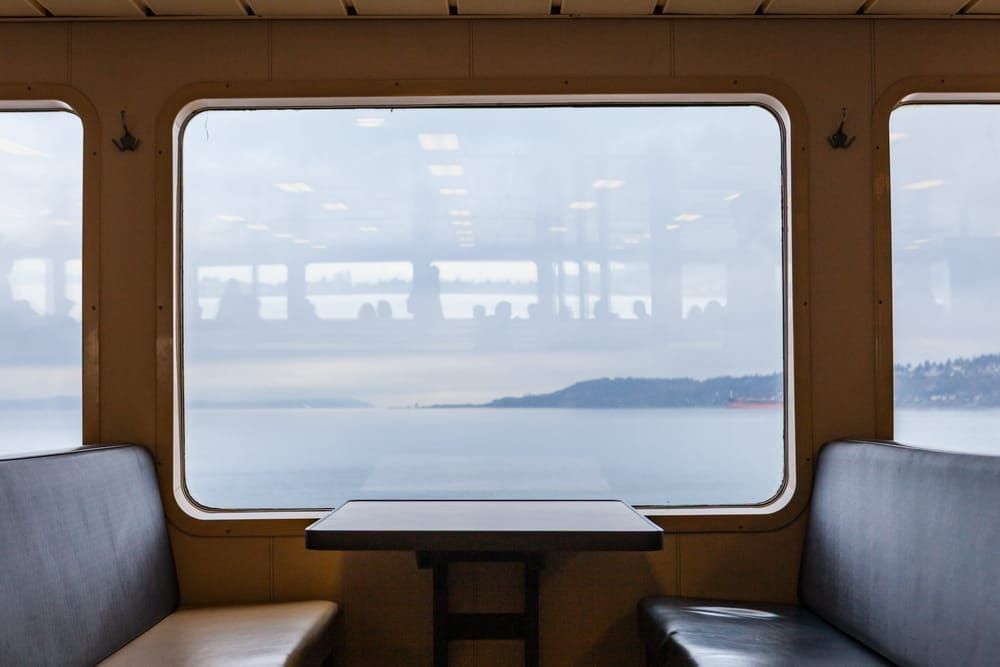 A seating area on a Washington State ferry with a table and window looking out on a cloudy day.