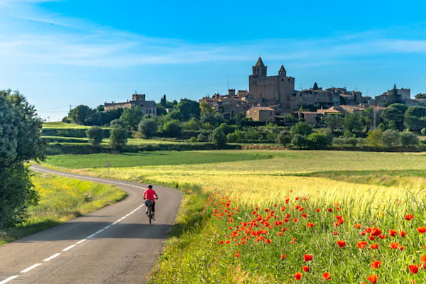 A Ride Through Time - Cyclist on a quiet road leading through a Mediterranean rural landscape