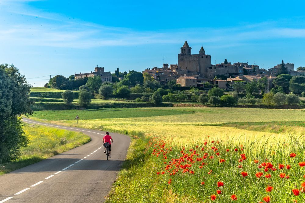 A Ride Through Time - Cyclist on a quiet road leading through a Mediterranean rural landscape