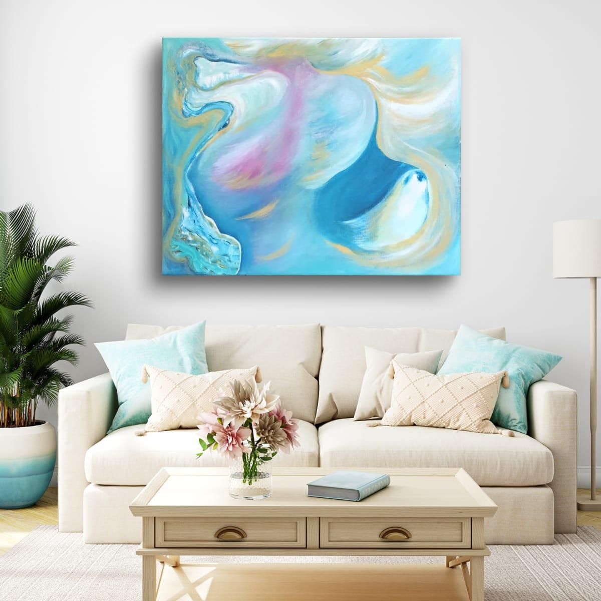 Intercessor open-edition fine art print by Anne Reid Artist above a cream sofa with teal cushions in a coastal living room
