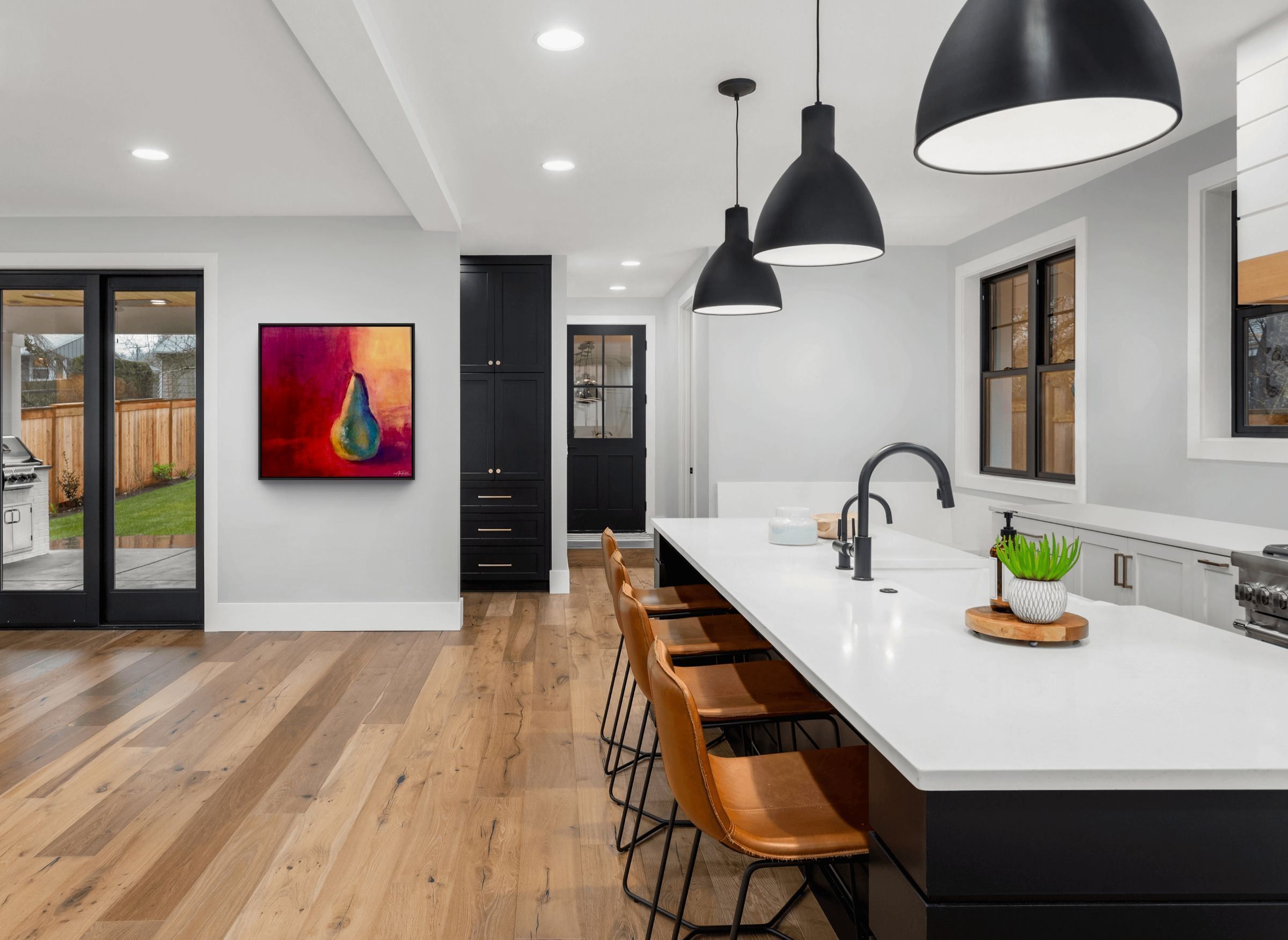 Pear, 36x36 canvas print by Anne Reid Artist shown in a contemporary kitchen setting with black cabinetry and warm oak floors